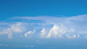 Enormous thunder clouds building in the extreme distance. against a bright blue. sky. taken from the window of an airliner. Video UltraHD