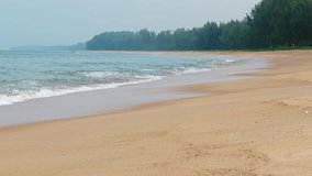 Gentle waves and sea foam wash over the coarse sand of a pristine. tropical beach paradise on a cloudy day. Video UltraHD