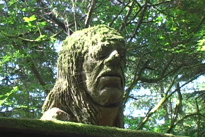 A huge wood carving of a mans face in the Redwood National Forest.