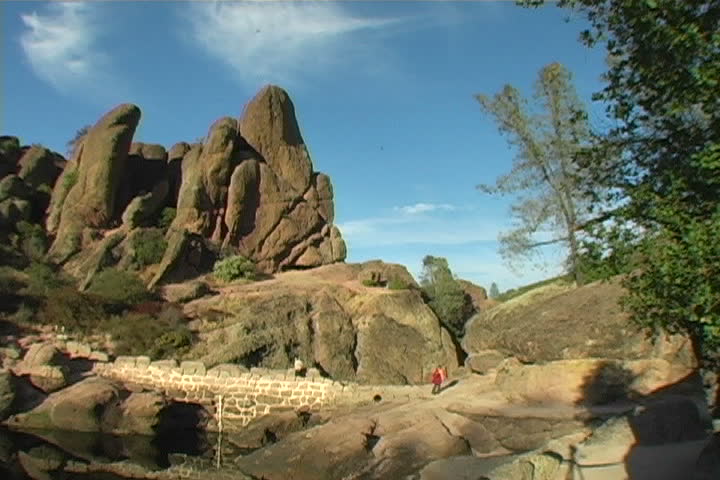 A wide-shot of two people hiking at Pinnacles National Monument.