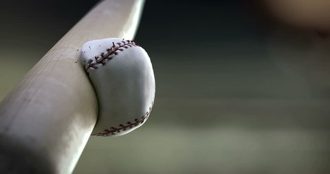 Super hit. Baseball bat hits the ball in slow motion, close-up, you can see how deformation ball and breaking seam thread