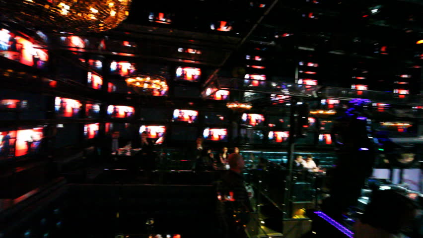 People sit near control panel at club with walls lined of many glowing monitors in checkerboard pattern, panorama left to right | Shutterstock HD Video #1484695