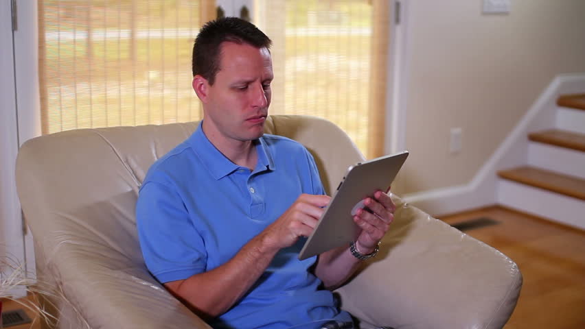 A man casually uses his touchscreen computer in his living room.