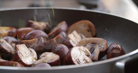 Mushrooms being cooked in pan sauteed by chef in kitchen slow motion 4K, delicious fungi breakfast in olive oil and butter