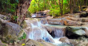 Waterfall flow through wet stones and rock cascades in beautiful tropical forest