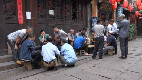 FENGHUANG, CHINA - 19 SEPTEMBER 2015: Groups of Chinese men play traditional chess (checkers) in a traditional looking setting, in Fenghuang