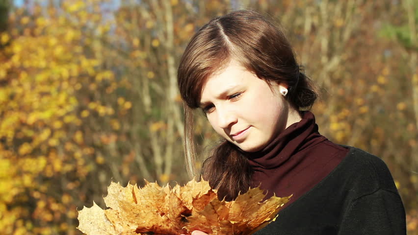 teen girl holding a bunch of leaves in autumn park