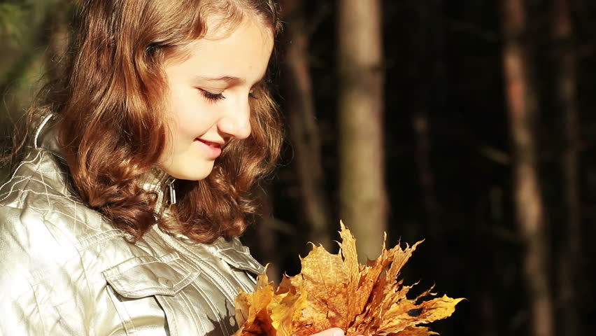 teen girl holding a bunch of leaves in autumn park