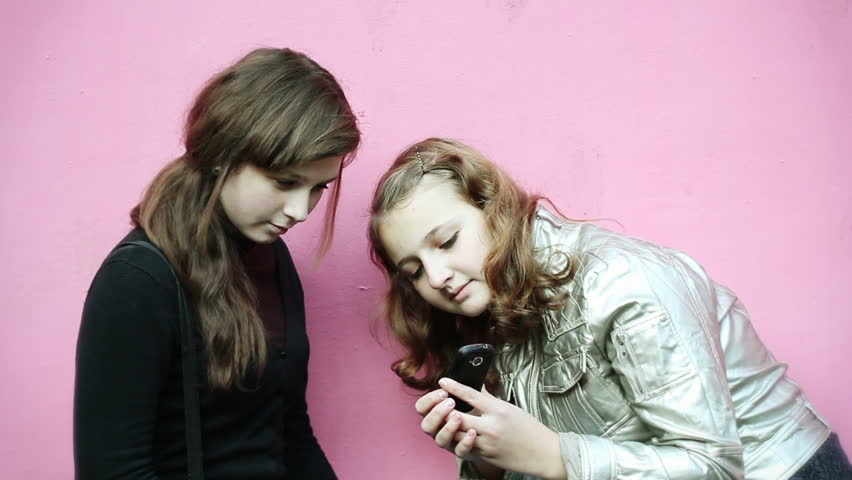 two teenage girls consider phone