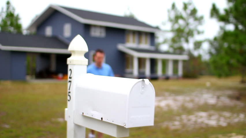 A man checks his mail outside of his house.