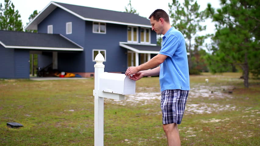 A man checks his mail outside of his house.