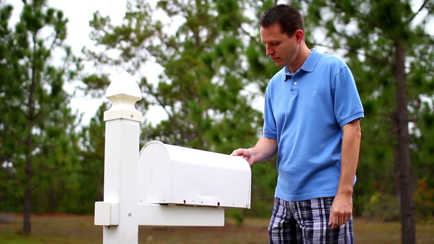 A worried man gets his mail outside of his house.