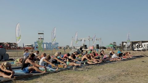 OLENEVKA/RUSSIA - AUG 03 2015: People Doing Stretching During a Training Yoga on the beach at the festival Extreme Crimea 2015