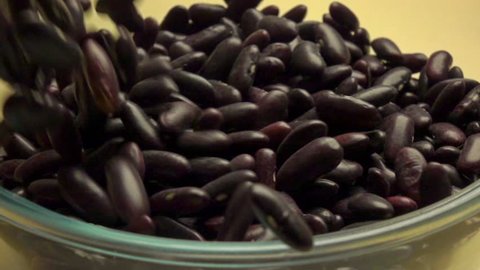 Pouring black beans into a glass bowl. Super slow motion macro video