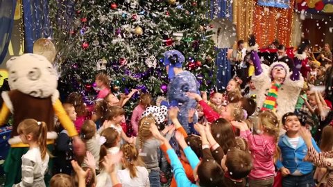 MOSCOW, RUSSIA - DEC 18, 2014: Little children and actors animators jump catching snowflakes around Christmas fir tree in hall of circus of dancing fountains Akvamarin.