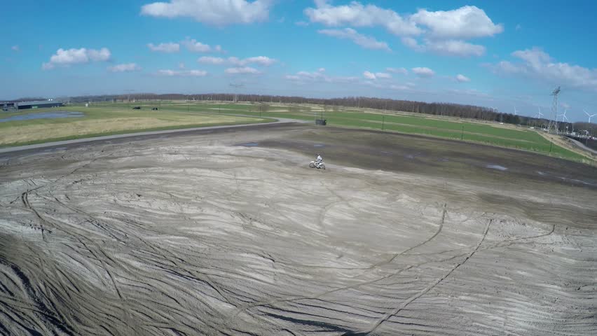 Aerial of motocross dirt track drone footage motorcross rider front and side off-road motorcycle racing held on enclosed off-road circuit with serveral corners jumps driving through sand mud dirt 4k