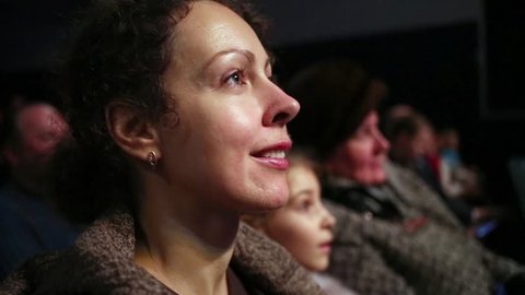 Closeup face in profile of young woman who laughs and claps hands watching performance at auditorium.: stockvideo