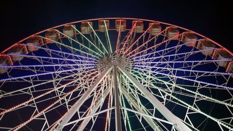 Spinning ferris wheel at night with lights, low angel