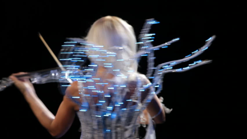 Magic violinist. Beautiful blonde girl playing the violin in a beautiful neon suit. 