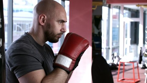 Bald caucasian boxer performing shadow boxing in gym