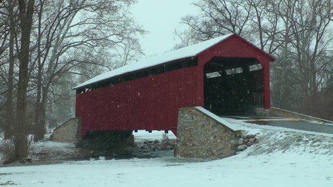 Snow falling during winter at covered bridge in rural Pennsylvania.