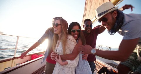 Group of multi ethnic friends standing close to each other on a yacht and posing for a group protrait at sunset