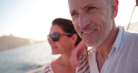 Close up shot of a retired couple looking lovingly at the ocean while enjoying a cruise on a yacht with clear blue sky and bright afternoon sunflare