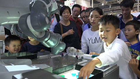 SHANGHAI, CHINA - 7 NOVEMBER 2015: Chinese children play a game against a robot at a technology and robotics trade fair in Shanghai, China