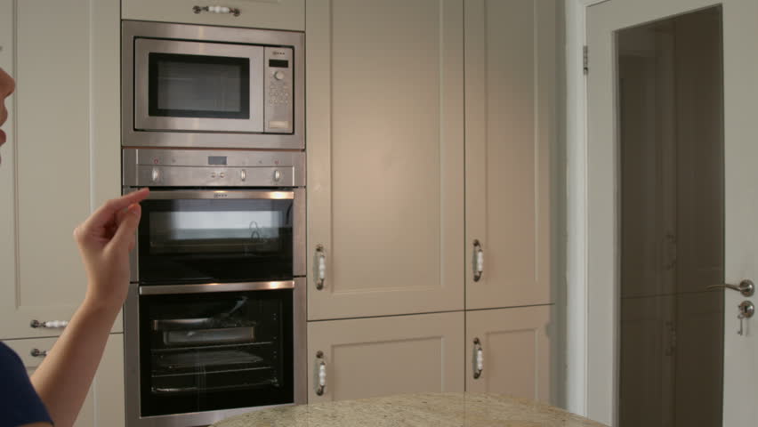 Pretty young woman usin invisible touchscreen in the kitchen