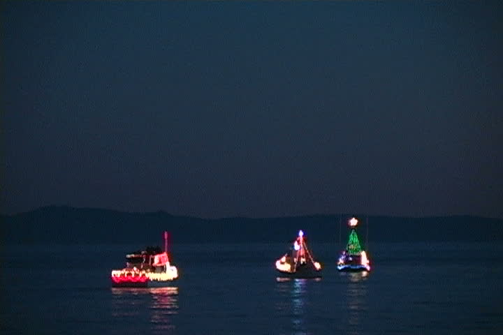 Three boats out at sea with Christmas lights.