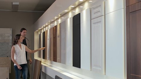 Couple browsing samples of cabinets cupboards in modern kitchen showroom home remodeling, renovation and makeover concept