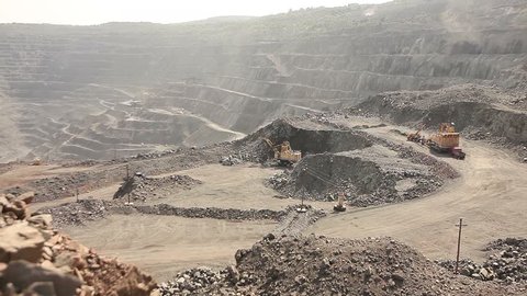 Large, open-pit iron ore mine showing the various layers of soil and iron rich ore,  industrial exterior, ore mining quarry, sunny day, summer, mining of iron
