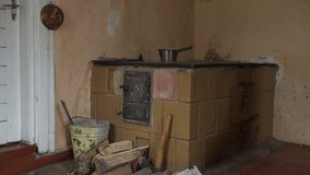 young girl put wood in old rustic clay oven in the cottage kitchen. video clip.