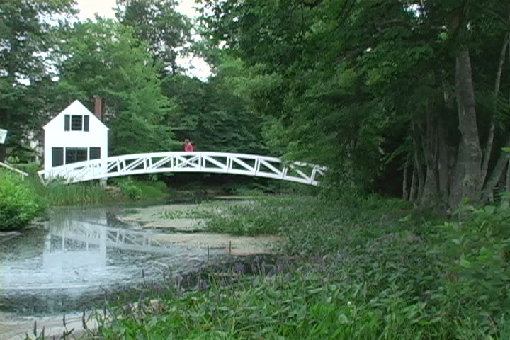 A woman walks across a foot bridge to her home in Maine.