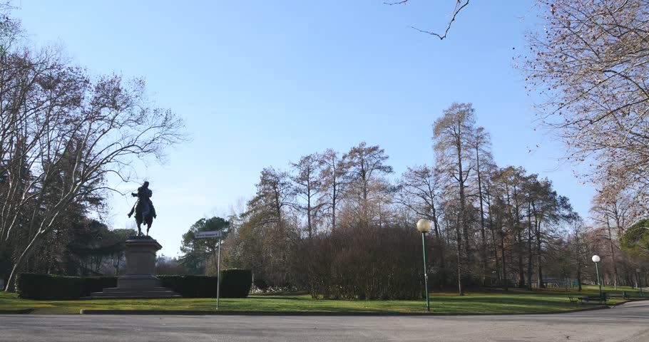 Men running in Regina Margherita Park in a sunny day with Vittorio Emanuele II statue in the background. Bologna, Italy.