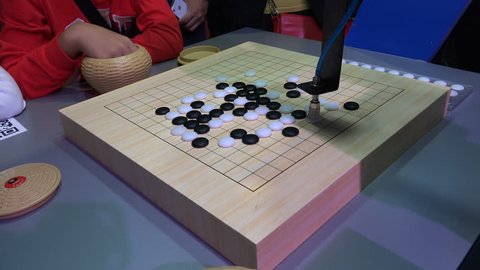 SHANGHAI, CHINA - 7 NOVEMBER 2015: A boy plays a game of traditional Chinese checkers ('go') against a robot, at an international robotics exhibition in Shanghai, China