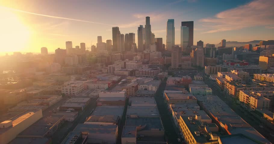 Aerial view of city of Los Angeles downtown skyline at sunset. Camera flying backward. 4K UHD.