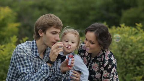 Happy young family blows soap bubbles