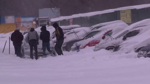 The guys are pushing a car stuck in the snow