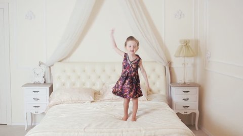 happy girl jumping and dancing on the bed