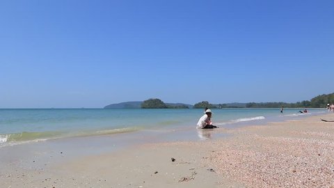 Beautiful Thai Beach. Nopparat Thara Beach near Krabi. Thai Lady looking for clams in the sand.