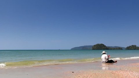 Beautiful Thai Beach. Nopparat Thara Beach near Krabi. Thai Lady looking for clams in the sand. Full HD footage.
