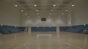 Basket Ball Court. Wide of an empty lit basketball court. The lights are switched off at the end of the clip.