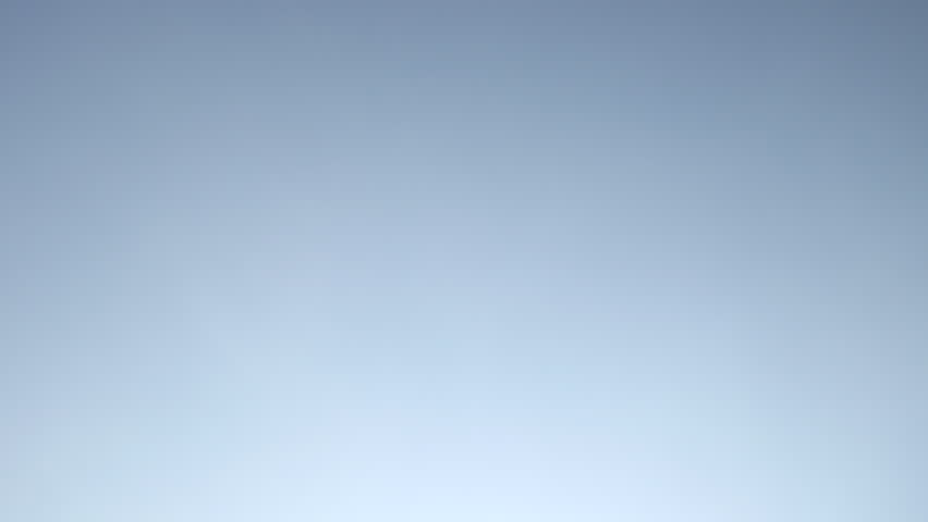 Saudi Arabian Flag. Semi-circular pan left on the Saudi flag against a blue sky. The flag billows in slow motion in the breeze.