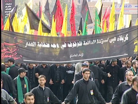 Dahieh, Beirut, Lebanon - 2005 - Hezbollah's Ashoura commemorations. A procession of people dressed in black chant Hezbollah slogans. Men hold a black banner commemorating the Battle of Kerbala.
