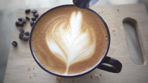 Stiring milk foam in a cup of latte coffee, slow motion 