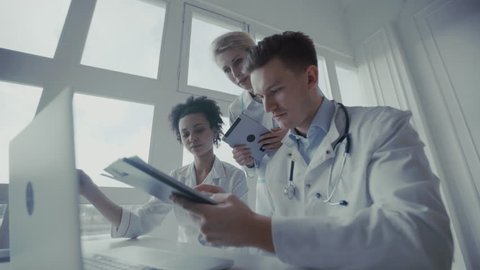 Healthcare, medical: Medical meeting. Group of multi-ethnic doctors discuss and looking x-ray in a clinic or hospital. UHD 4K