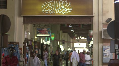 Kuwait Souk. 2013 Medium shot of the entrance sign of Souk Al Moubarakiya written in Arabic calligraphy. Shoppers and traders walk in and out of the souk.
