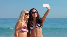 Video of happy pretty friends taking a selfie at the beach