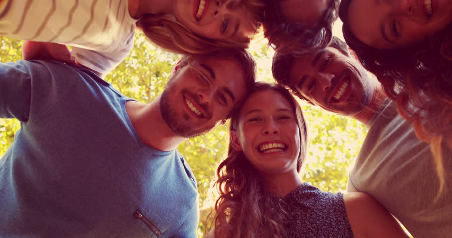 Happy friends smiling at camera in the park on a sunny day